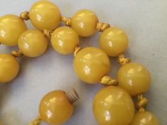 "Lovely egg yolk Bakelite single strand necklace. Hand tied graduated beads. Romantic, yellow necklace. Hidden bead clasp. Simply beautiful, gleaming, set of beads. Large knot, hand tied 1930s style. Chunky! Graduated beads: 8mm (smallest) to 17mm (largest) 15 1/2\" necklace Attention: All items are listed to the best of our observation, but they are pre-owned and pre-loved (meaning we may have missed something minor and/or be in need of light cleaning.) Please read our shop policies and/or conv Yellow Costume Jewelry Necklace For Formal Occasions, Yellow Costume Jewelry Necklace For Formal Events, Classic Yellow Round Bead Jewelry, Vintage Yellow Single Strand Jewelry, Formal Yellow Jewelry With Round Beads, Vintage Polished Yellow Beads Jewelry, Vintage Yellow Round Bead Necklaces, Yellow Single Strand Beads For Jewelry Making, Vintage Yellow Jewelry With Polished Beads