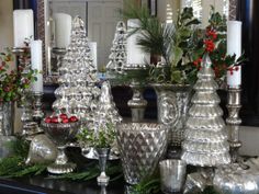 a table topped with lots of silver vases and candles