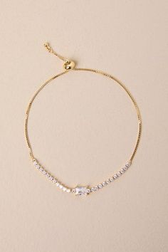 Decadent occasions require sparkling accessories like the Lulus Perfectly Upscale Gold Rhinestone Tennis Bracelet! Shiny, gold-toned metal shapes this chic bracelet that has a slender box chain that supports a band of glittering rhinestones at the front, all surrounding a central, baguette-cut rhinestone. Toggle clasp closure makes this adorable piece adjustable, as an added bonus! Toggle clasp closure. Bracelet measures 3" long with 4" slide adjustments on each side. Man Made Materials. Importe Elegant Gold Chain Bracelet With Sparkling Stones, Dainty Gold Sparkling Bracelet, Gold Chain Bracelet With Sparkling Stones For Formal Events, Gold Chain Bracelet With Sparkling Stones For Formal Occasions, Formal Gold Chain Bracelet With Sparkling Stones, Adjustable Gold Crystal Tennis Bracelet, Elegant Metal Tennis Bracelet For Parties, Gold Sparkling Adjustable Crystal Bracelet, Chic Bracelet