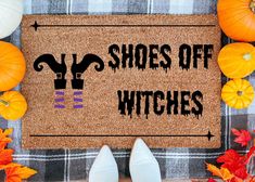 a door mat with the words shoes off witches on it surrounded by pumpkins and gourds