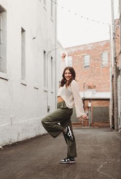 a woman standing in the middle of an alleyway with her arms up and legs spread out