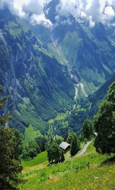 the mountains are covered in green grass and trees, with a road winding through them