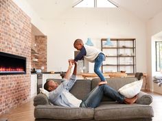 two men are sitting on a couch and one is holding the other's leg