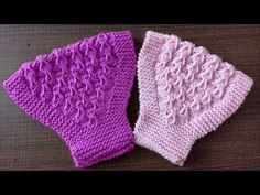 two knitted mittens sitting next to each other on top of a wooden table