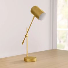 a gold desk lamp sitting on top of a wooden table