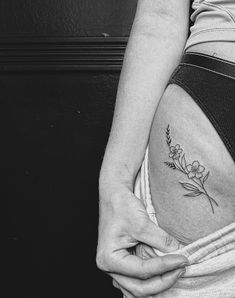 black and white photo of a woman's stomach with flower tattoo on the side