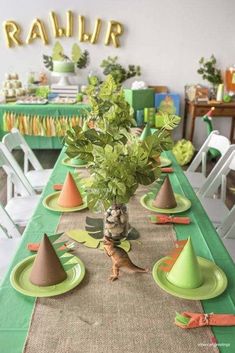 a long table with green and orange plates, napkins and small plants in a vase