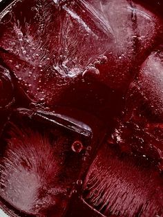 an overhead view of ice and water in a metal bowl with red liquid on it