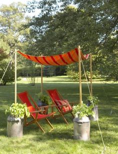 two red lawn chairs sitting on top of a lush green field