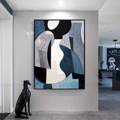 an abstract painting hangs on the wall next to a black and white table with two chairs