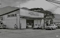 an old gas station with cars parked in front