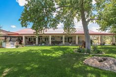 a large house sitting on top of a lush green field next to a tree in front of it