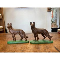 two figurines of dogs standing on top of a wooden table