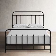 a black metal bed frame with white pillows