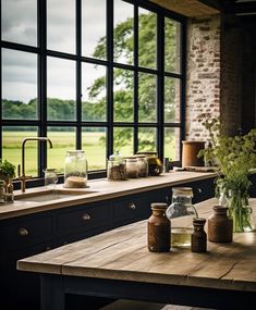 a table with jars and vases on it in front of a window that looks out onto a field