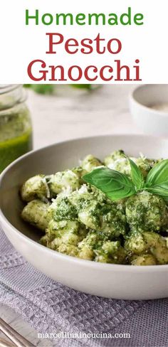 a white bowl filled with pesto gnocchini and topped with fresh basil