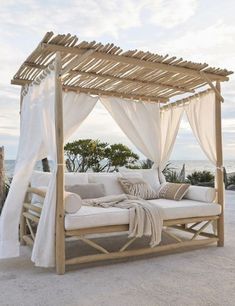 an outdoor day bed with white curtains and pillows