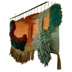 a wall hanging made out of woven material with fringes and tassels on it