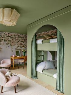 a bedroom with bunk beds and green curtains on the walls, along with a pink chair