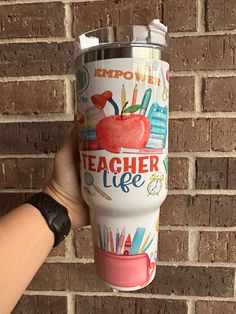 a person holding up a cup that says teacher life on it and an apple in the middle