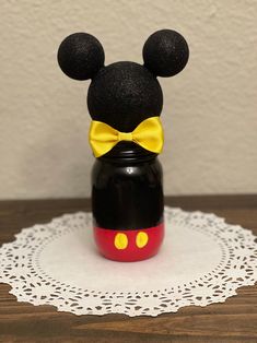 a black and red mickey mouse jar with a yellow bow on it's head