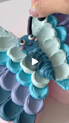 someone is decorating a cake with blue and purple icing