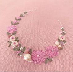 a pink necklace with flowers and pearls on it