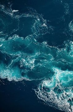 an aerial view of the ocean with blue water and foamy waves on the surface