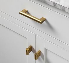 a white cabinet with gold handles and knobs