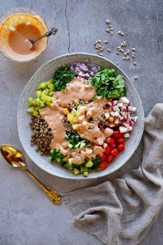 a white bowl filled with salad and dressing next to a glass of orange juice on the side