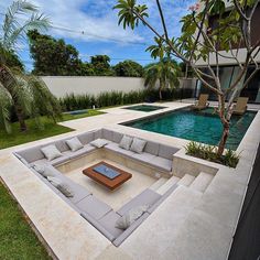 a couch sitting on top of a stone patio next to a swimming pool and palm trees