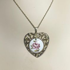 About This one is a real treasure. A Victorian cabbage rose with leaves and twigs have been hand painted on a pure white semi-precious stone. This pendant is dainty and delicate. It has intricate filigree metalwork on the metal heart. One of kind. Estate jewelry. RARE.  Condition: Pre-Owned (see photos).  Dimensions: Width 2.5 in., Height 3 cm. including bail (best approximations).  Item pictured is the EXACT item being sold (see photos for exact details as they are the best representations of t Vintage Rose Design Jewelry For Valentine's Day, White Jewelry With Rose Design As Gift, Vintage White Heart-shaped Jewelry, Hand Painted Heart Necklace For Gifts, White Jewelry With Rose Design For Gift, Hand Painted Heart Necklace For Gift, Vintage White Heart Pendant Jewelry, Hand Painted Heart-shaped Jewelry For Gifts, Silver Heart-shaped Jewelry With Rose Design