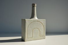 a bottle shaped like a building with a rainbow on the side and a small arch at the top