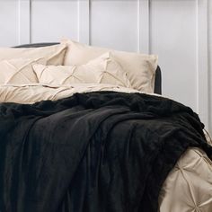 a bed with black and white comforter on it's headboard next to a night stand