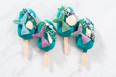 three little mermaid lollipops sitting on top of each other in blue and green