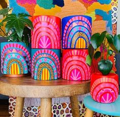 colorfully painted vases sit on top of a table next to a potted plant