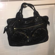 A Large Black Bag, Leather Material With Gold Zippers. Three Pockets On The Outside Front And Pocket On The Back. One Interior Pocket. In Good Condition. If You Have Any Further Questions Feel Free To Message Me. Casual Black Shoulder Bag With Gold-tone Hardware, Black Shoulder Bag With Gold-tone Hardware For Everyday, Black Canvas Satchel For Errands, Black Satchel With Gold-tone Hardware For Everyday, Everyday Black Satchel With Gold-tone Hardware, Black Hobo Tote Bag With Gold-tone Hardware, Black Hobo Bag With Gold-tone Hardware, Black Satchel With Gold-tone Hardware Shoulder Bag, Trendy Black Hobo Bag With Gold-tone Hardware