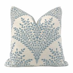 a blue and white pillow with leaves on it's side, in front of a white background