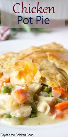 chicken pot pie on a plate with broccoli, carrots and peas in it