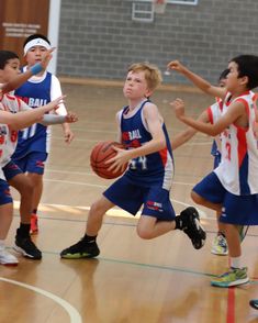 several young boys playing basketball in a gym