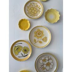 yellow and white plates with flowers on them are arranged in a row against a white wall