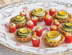 small appetizers with cucumbers and tomatoes are on a floral platter