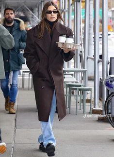 a woman walking down the street holding a coffee cup