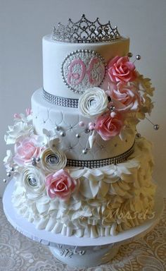 two tiered wedding cake with pink roses on top and white ruffles around the edges