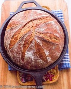 a loaf of bread sitting on top of a wooden cutting board next to a blue and white towel