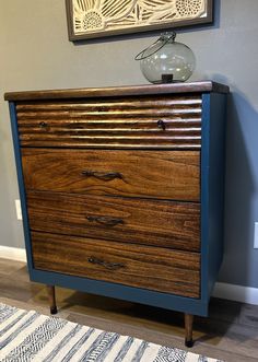 a wooden dresser with two drawers and a vase on top