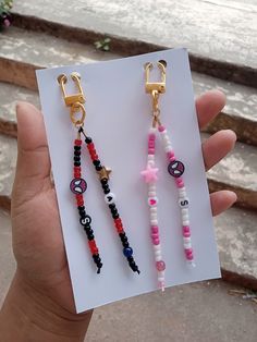 a person holding up two different colored beaded earrings