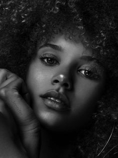 a black and white photo of a woman's face with her hand on her chin