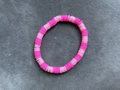 a pink beaded bracelet sitting on top of a gray surface