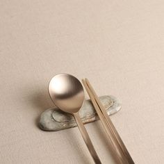 two spoons and one fork sitting on top of a stone plate next to each other